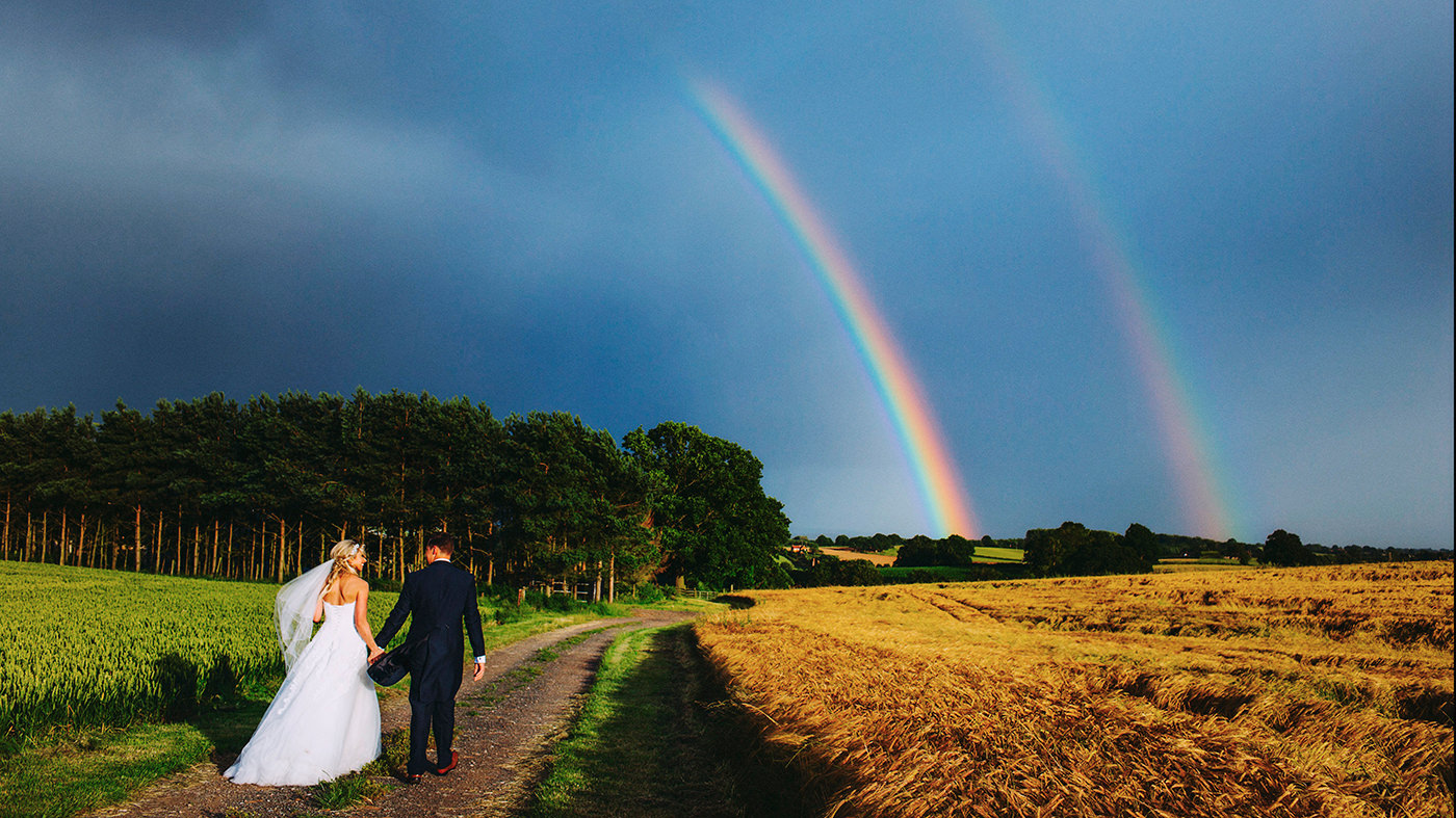 Bride and grrom with double rainbow at a UK wedding
