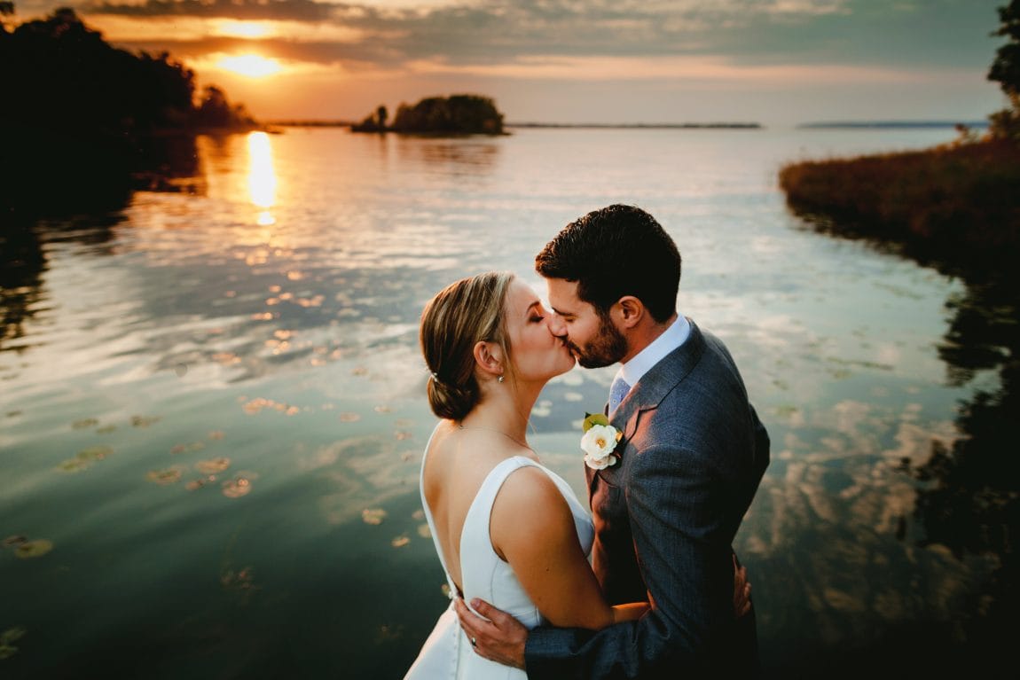 Bride and groom kissing at sunset